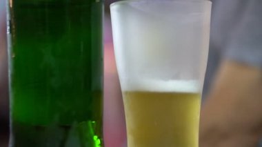 Buzlu bira cam içinde altın içkiyle. 4k kadar yakın yeşil şişe
