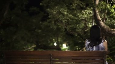 Asyalı kadın geri, yemyeşil güzel tropikal bahçe Park bankta oturmuş