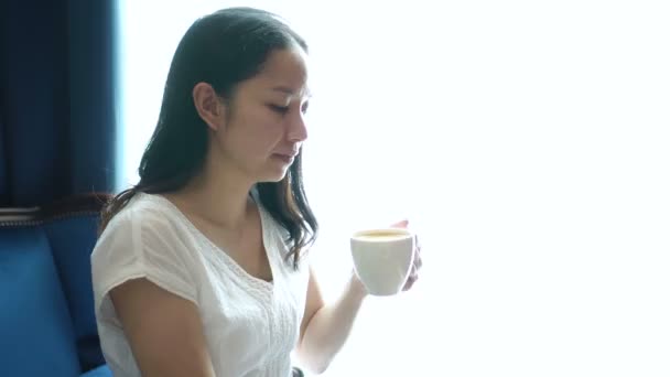 Asiática Mujer Sentada Iluminado Ventana Beber Taza Café Relajarse Feliz — Vídeo de stock