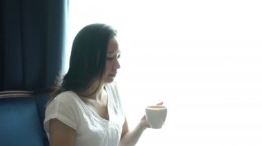 Asyalı kadın ışıklı pencere bardak kahve, oturup dinlenmek ve mutlu