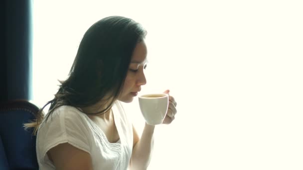 Mulher Asiática Sentado Janela Iluminada Beber Xícara Café Relaxar Feliz — Vídeo de Stock