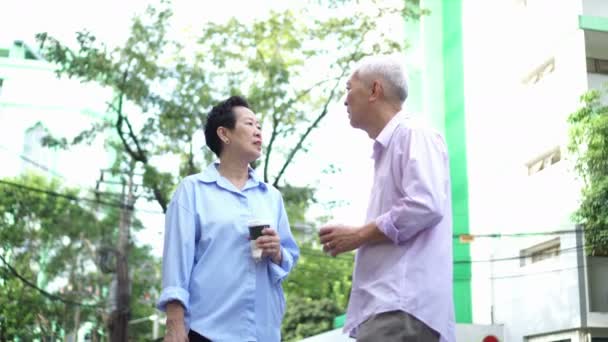亚洲老年夫妇走在城市大厦与带走早晨咖啡 — 图库视频影像
