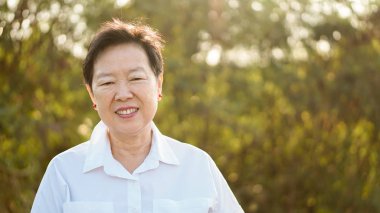 Sabah güneş yeşil doğa arka plan ile gülümseyen mutlu Asyalı yaşlı kadın