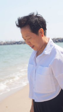 Mutlu Asyalı yaşlı kadın sakin plaj deniz ve güneş yavaş hayat