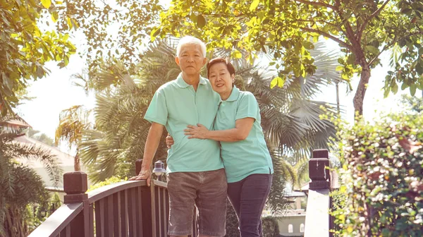 Asian elderly couple laugh together in green natural park background
