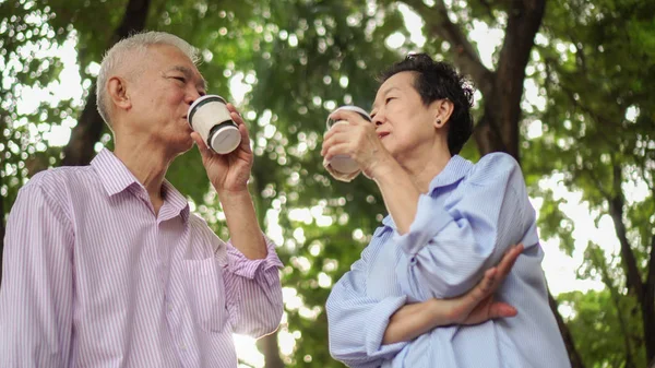 幸せなアジア高齢者カップル コーヒーを飲みながら緑豊かな街で朝散歩 — ストック写真