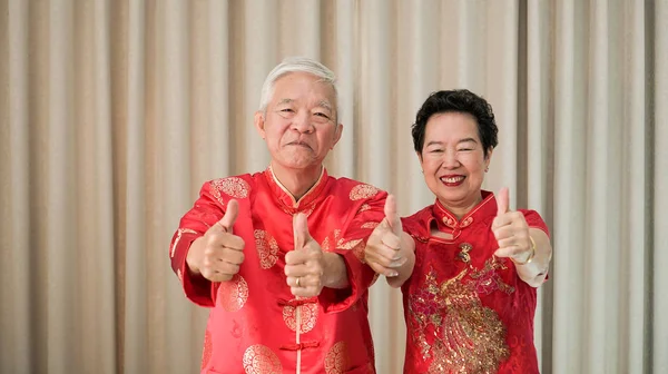 中国老年夫妇穿着红色服装大拇指的手势 — 图库照片