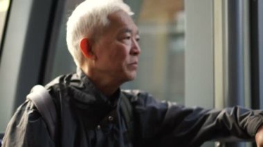 Asyalı kıdemli adam toplu taşıma araçlarını kullanırken düşünüyor