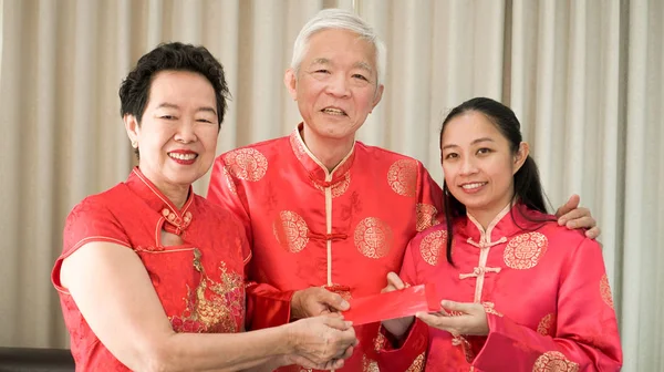 Os pais asiáticos dão envelope vermelho à filha Ano Novo Chinês — Fotografia de Stock