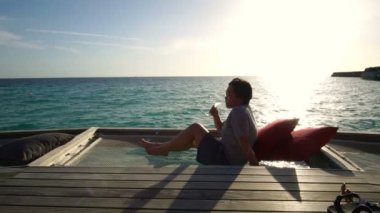 Zengin şişman Asyalı kadın Maldive lüks tatil günbatımı ve kokteyl rahatlatıcı