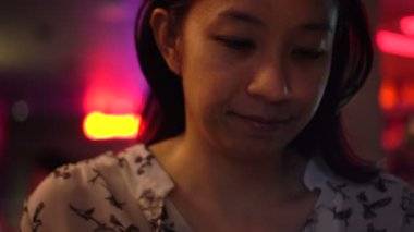 Kırmızı neon modern gece kulübünde akıllı telefon kullanan Asyalı kadın