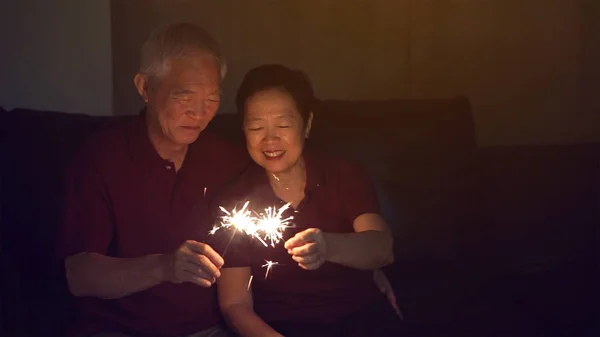 Ασιατικό ζευγάρι ηλικιωμένων γιορτάζοντας μαζί στο σπίτι λάμπει firewo — Φωτογραφία Αρχείου