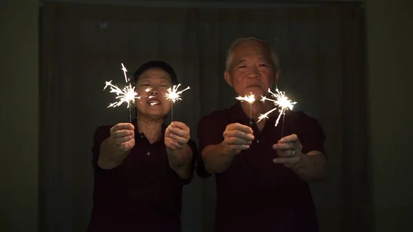 亚洲老年夫妇玩火花，晚上爆竹。Co — 图库照片