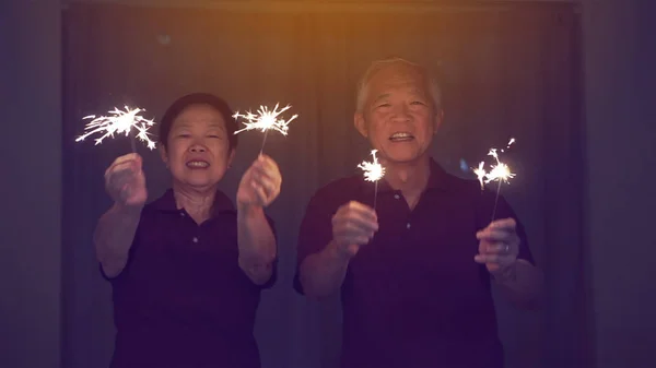 Asiatiska Senior par spelar Sparklers, brand kracker på natten. Co — Stockfoto