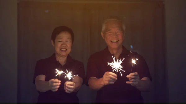 Casal sênior asiático jogando sparklers, fogo cracker à noite. Co — Fotografia de Stock