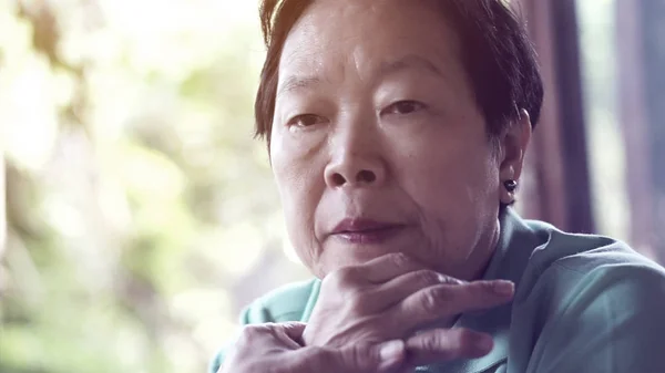 Asian senior woman with hand on face thinking, worry sad — Stock Photo, Image