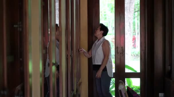 家の図書館チークキャビネットで物を探しているアジアのシニア女性 — ストック動画