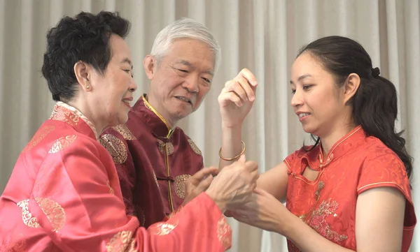 Asijští rodiče dávají dceru do zlatého držáku čínský Nový rok — Stock fotografie