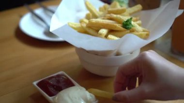 Patates kızartması yiyen eller. Mayonezli ketçap sosu.