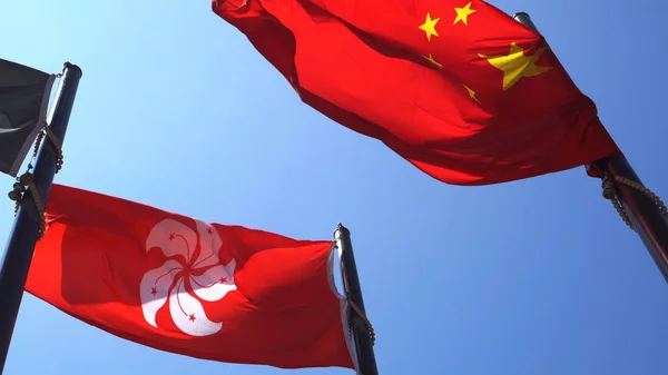 Hongkong en vasteland China rode vlaggen in de blauwe lucht. Intern beleid — Stockfoto