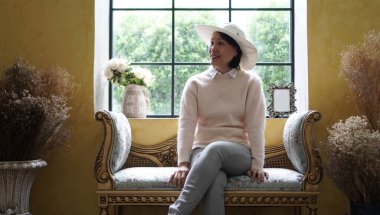 Avrupa tarzı pencere kenarında oturan güzel Asyalı kadın lüks tatil gezisinde.