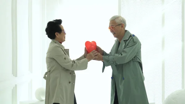 Asian elder senior couple thrown red heart balloon give and receive love marriage life