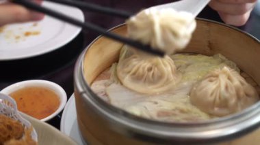 El yemek çubukları Çin restoranında xiaolongbao çorbası yiyor.