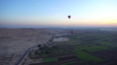 Güneş doğarken, Kral Unesco miras bölgesinin Luxor Mısır vadisinde sıcak hava balonuna binerken çekilmiş bir video.