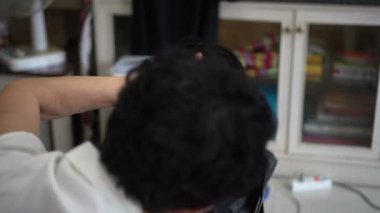 Asyalı anne, karantina zamanında aile yadigarı berber için evde saç kesimi yapıyor.