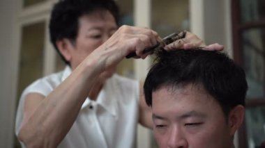 Asyalı anne, karantina zamanında aile yadigarı berber için evde saç kesimi yapıyor.