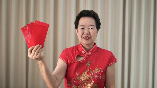 幸せなアジアのシニア女性中国の旧正月の赤い封筒で伝統的な衣装 — ストック写真