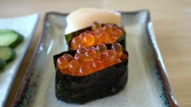 Çubuklar somon yumurtası yiyor suşi ikura maki Japon yemeği.