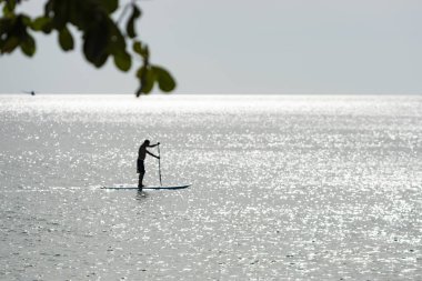 Bir adam bir raket Lonely Beach, Koh Chang Adası, Tayland sörf yapan.
