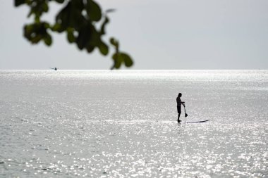 Bir adam bir raket Lonely Beach, Koh Chang Adası, Tayland sörf yapan.