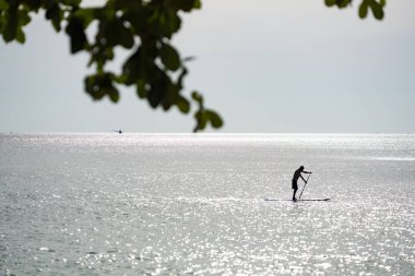 Bir adam bir raket Lonely Beach, Koh Chang Adası, Tayland sörf yapan.