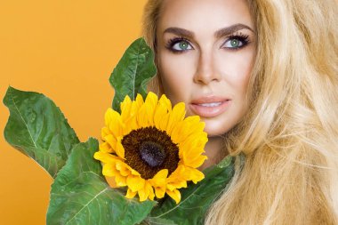 Uzun sarı saçlı ayçiçeği holding beyaz bir elbise giyen güzel bir kadın portresi.