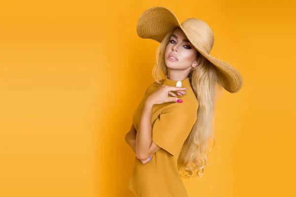 ブロンドの髪を持つ美しい セクシー エレガントな女性のエレガントな黄色の服と帽子でスタジオでポーズします — ストック写真