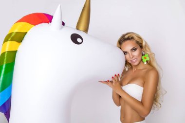 Güzel, seksi sarışın model şişme bir tek boynuzlu at ile zarif bir bikini. Yaz vurmak