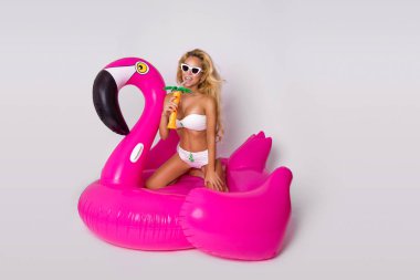 Zarif bir bikini, güzel, seksi sarışın model pembe flamingo üzerinde yatıyor. Yaz vurmak
