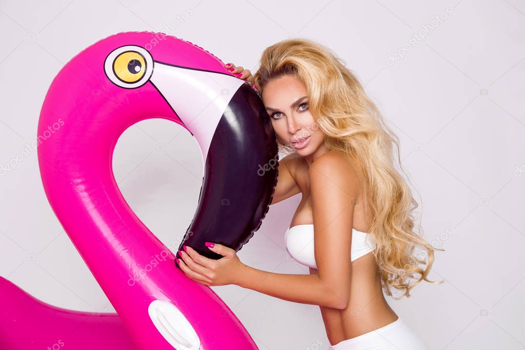 Beautiful sexy blonde model in a elegant bikini with a pink flamingo. Hit the summer
