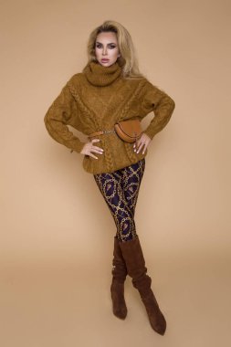 Stüdyoda bej renkli bir arka plan üzerinde bir sonbahar-kış giyim güzel kadın modeli