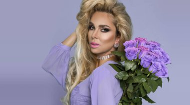 Bir buket gül tutan şık elbiseli güzel sarışın model. Mavi bir arka plan üzerinde Sevgililer ve Doğum günü hediye.