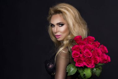 Bir buket kırmızı gül tutan şık elbiseli seksi güzel sarışın model. Sevgililer'ın hediye siyah bir zemin üzerine.