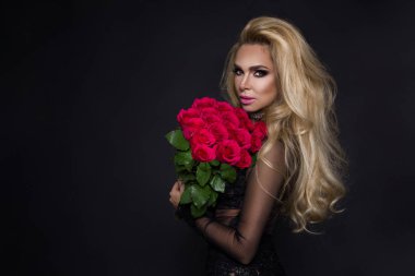 Bir buket kırmızı gül tutan şık elbiseli seksi güzel sarışın model. Sevgililer'ın hediye siyah bir zemin üzerine.