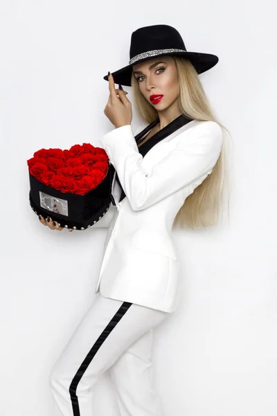 バレンタインの美しさ バラと赤いハートとエレガントな女の子 ギフトや帽子 背景の分離を持つ若い女性モデルのポートレート 幸せな若い美人フラワー ボックスを提示 — ストック写真
