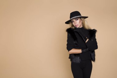 Bej arka planda izole edilmiş yüksek model kız portresi. Stüdyoda şık kıyafetler içinde poz veren zarif sarışın kadın. Günlük tarz, güzellik aksesuarları. Şapka ve eldivenler zarif kadınlar.