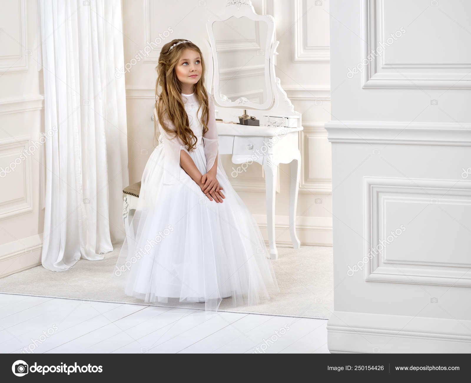 Portrait of cute little girl on white dress and wreath on first holy  communion background church gate - Image. Young model in the white  communion dress stands in an elegant palace Stock
