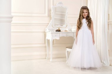 Beyaz elbise sevimli küçük kız ve çelenk ilk Komünyon arka plan kilise kapısı - görüntü üzerinde portresi. Zarif bir sarayda beyaz komünyon elbiseli genç modeli standları