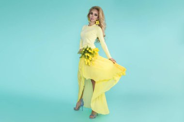 Bahar kadın. Bir buket bahar çiçek tutan güzellik yaz modeli kız renkli giysileri ile. Bu güzel hanımla mavi zemin üzerine Sarı laleler.