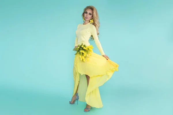 春の女性 夏モデル美少女カラフルな服を着て 春の花のブーケを保持しています 青い背景に黄色のチューリップを持つ美しい女性 — ストック写真